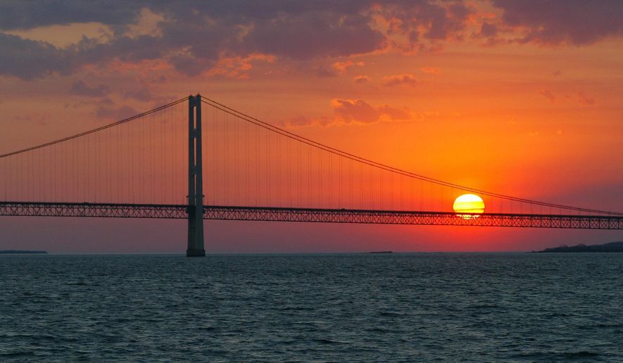 The sun sets over the Mackinac Bridge, the dividing line between Lake Michigan and Lake Huron, at Michigan's Mackinac Straits on May 31, 2002. Studies predict the Great Lakes and other large freshwater bodies around the world will move toward acidity as they absorb excess carbon dioxide from the atmosphere, which also causes climate change. Experts say acidification could disrupt aquatic food chains and habitat. (AP Photo/Al Goldis, File)