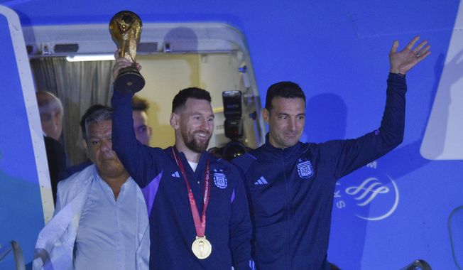 Argentina&#x27;s Lionel Messi holds the FIFA World Cup trophy as he deplanes, with coach Lionel Scaloni, in Buenos Aires, Argentina, Tuesday, Dec. 20, 2022. (AP Photo/Gustavo Garello)