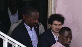 FTX founder Sam Bankman-Fried, second right, is escorted out of Magistrate Court toward a Corrections van, following a hearing in Nassau, Bahamas, Monday, Dec. 19, 2022. (AP Photo/Rebecca Blackwell)