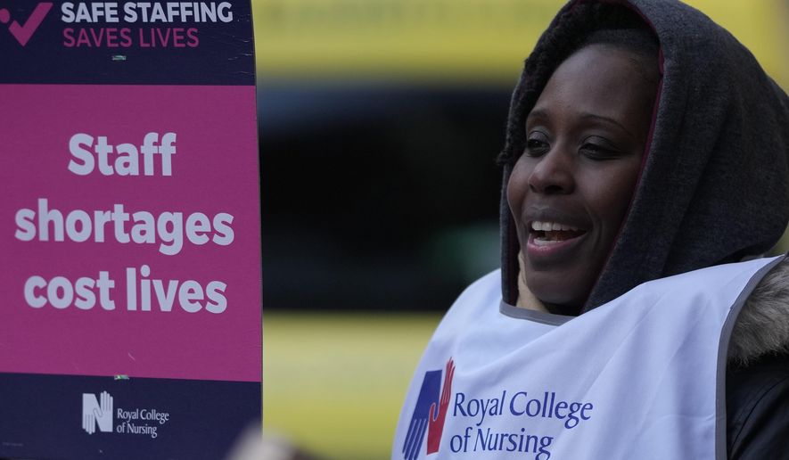 A nurse holds a placard on the picket line as she participates in a strike action over pay in London, Tuesday, Dec. 20, 2022. Nurses in England, Wales and Ireland will stage the biggest strike in the history of the Royal College of Nursing (RCN). Up to 100,000 members will walk out at 65 NHS (National Health Services) organisations. (AP Photo/Alastair Grant)