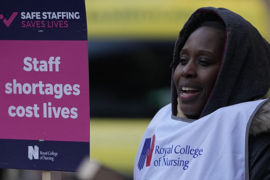 A nurse holds a placard on the picket line as she participates in a strike action over pay in London, Tuesday, Dec. 20, 2022. Nurses in England, Wales and Ireland will stage the biggest strike in the history of the Royal College of Nursing (RCN). Up to 100,000 members will walk out at 65 NHS (National Health Services) organisations. (AP Photo/Alastair Grant)