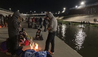 Migrants congregate at campfires on the banks of the Rio Grande in Ciudad Juárez, Mexico, as others wade through shallow waters toward the United States and its border wall on Tuesday, Dec. 20, 2022. Restrictions that prevented many from seeking asylum in the U.S. remained in place beyond their anticipated end. (AP Photo/Morgan Lee)