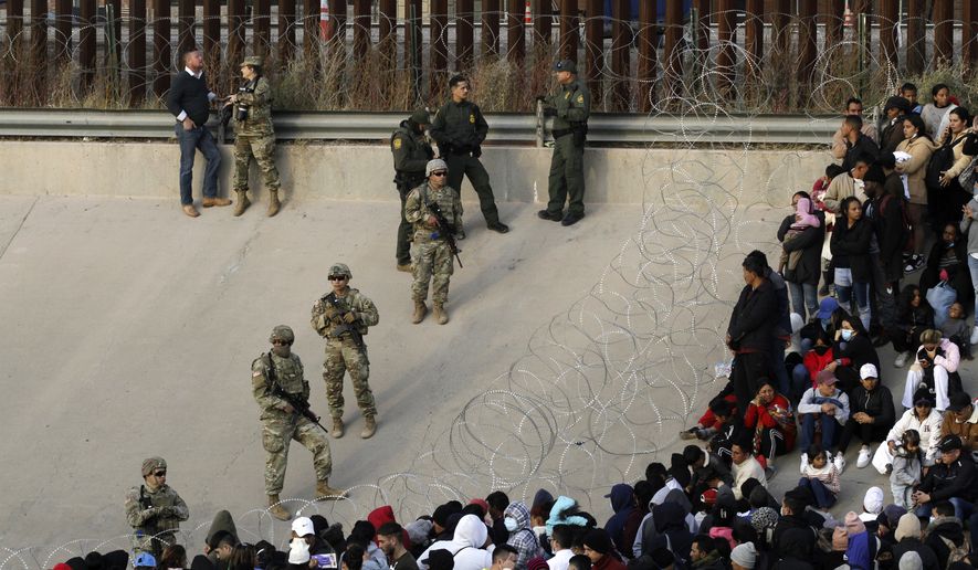 Migrants congregate on the banks of the Rio Grande at the U.S. border with Mexico on Tuesday, Dec. 20, 2022, where members of the Texas National Guard cordoned off a gap in the U.S. border wall. Restrictions that prevented many from seeking asylum in the U.S. remained in place beyond their anticipated end. (AP Photo/Morgan Lee)