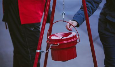 A donor prepares to give at a Salvation Army red kettle during the Christmas season. The evangelical church and social services organization says donations are down 8% this year. (Photo courtesy of The Salvation Army)