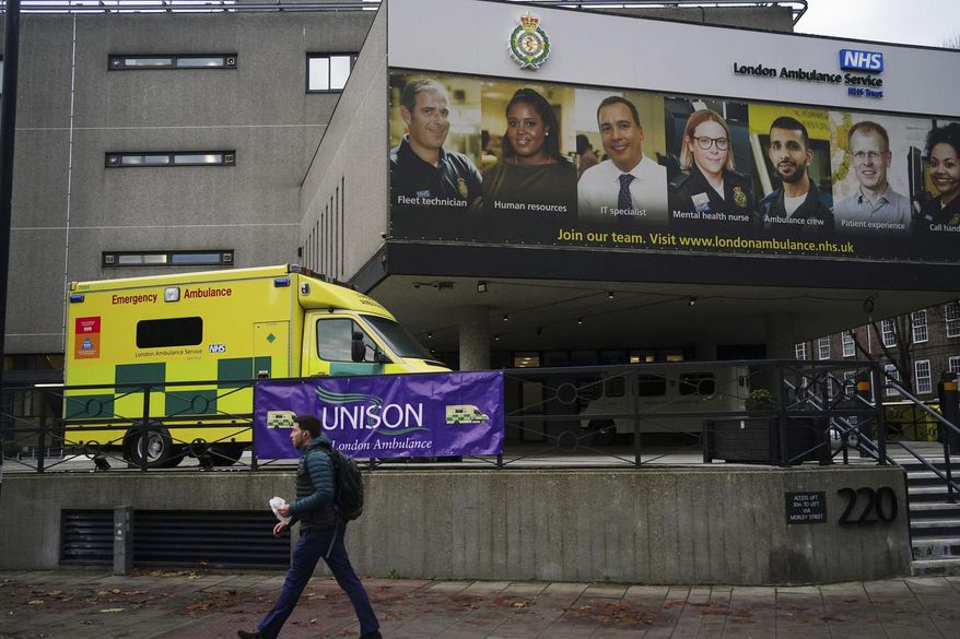 A man walks past Waterloo ambulance station as paramedics, ambulance technicians and call handlers in England and Wales take strike action in England and Wales, in London, Wednesday, Dec. 21, 2022. Thousands of ambulance workers in Britain are staging a 24-hour strike, with unions and the government swapping accusations of blame for putting lives at risk. The government is telling people not to play contact sports, take unnecessary car trips or get drunk in order to reduce their risk of needing an ambulance on Wednesday. (Victoria Jones/PA via AP)