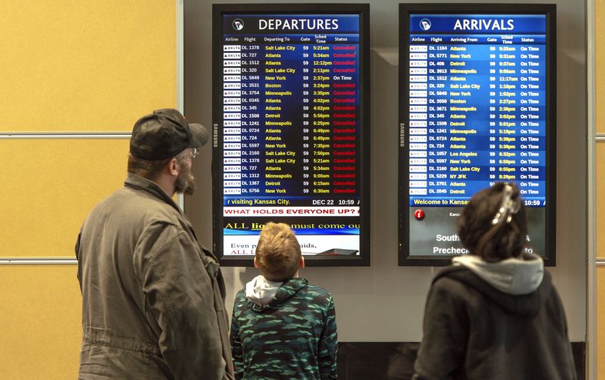Travelers look at a list of canceled flights at Kansas City International Airport on Thursday, Dec. 22, 2022, in Kansas City, Mo. (Nick Wagner/The Kansas City Star via AP)