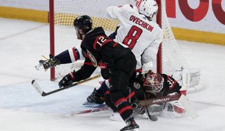 Washington Capitals left wing Alex Ovechkin (8) collides with Ottawa Senators goaltender Cam Talbot, bottom right, and right wing Alex DeBrincat (12) during third period NHL action, Thursday, December 22, 2022 in Ottawa. THE CANADIAN PRESS/Adrian Wyld/The Canadian Press via AP)