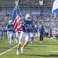 This Oct. 22, 2022, photo provided by University of Buffalo Athletics shows University at Buffalo NCAA college football player Damian Jackson (38) carrying the American flag as the team takes the field before a game against Toledo, in Buffalo, N.Y. Jackson has no expectation of growing emotional in preparing to play the final game of his college career next week. (Paul Hokanson/Univ. of Buffalo Athletics via AP)