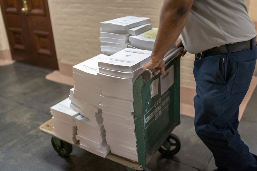 Stacks of the Congressional Record are distributed as lawmakers debate a massive $1.7 trillion spending bill that finances federal agencies and provides aid to Ukraine, at the Capitol in Washington, Friday, Dec. 23, 2022. (AP Photo/J. Scott Applewhite)