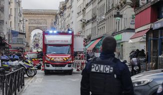 A police officer stands next to the cordoned-off area where a shooting took place in Paris, Friday, Dec. 23, 2022. Multiple people have been wounded and one person arrested after a shooting in central Paris on Friday, authorities said. Police cordoned off the area in the 10th arrondissement of Paris and the Paris police department warned people to stay away from the area. It said one person was arrested, without providing details. (AP Photo/Lewis Joly)