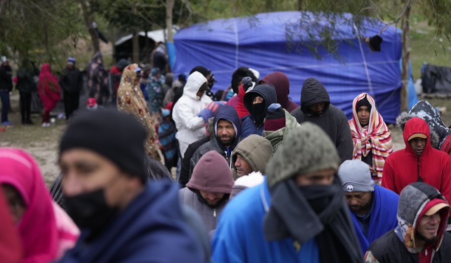 Migrants from Venezuela line up in the cold weather for hot drinks and food from volunteers at a makeshift camp on the U.S.-Mexico Border in Matamoros, Mexico, Friday, Dec. 23, 2022. Migrants are waiting on a pending U.S. Supreme Court decision on asylum restrictions. (AP Photo/Fernando Llano)
