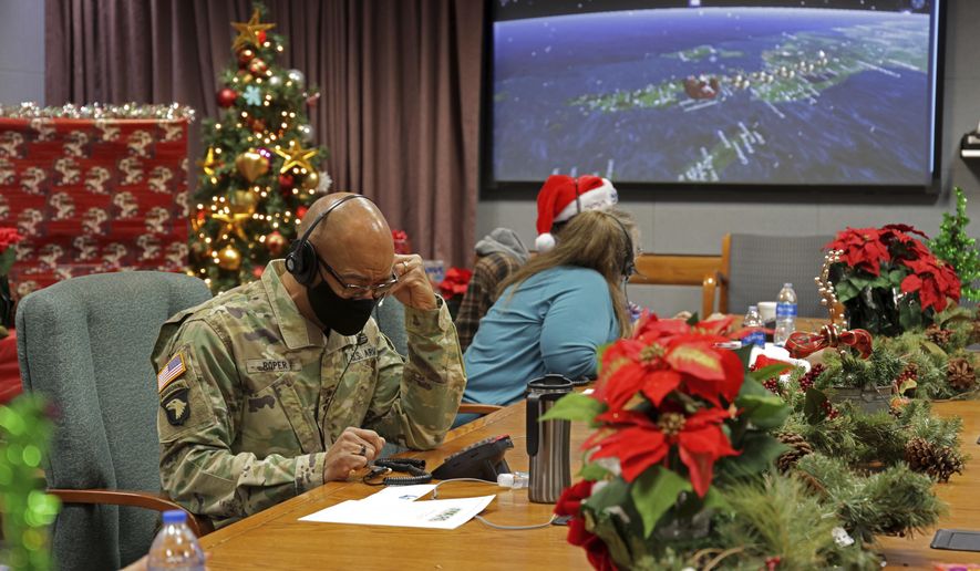 In this photo released by the U.S. Department of Defense, volunteers answer phones and emails from children around the globe during annual NORAD Tracks Santa event at Peterson Air Force Base in Colorado Springs, Colo., on Dec. 24, 2021. The U.S. military agency known for tracking Santa Claus as he delivers presents on Christmas Eve doesn't expect COVID-19 or the "bomb cyclone" hitting North America to impact Saint Nick's global travels this year. NORAD, the North American Aerospace Defense Command, is responsible for monitoring and defending the skies above North America. (Jhomil Bansil/U.S. Department of Defense via AP)