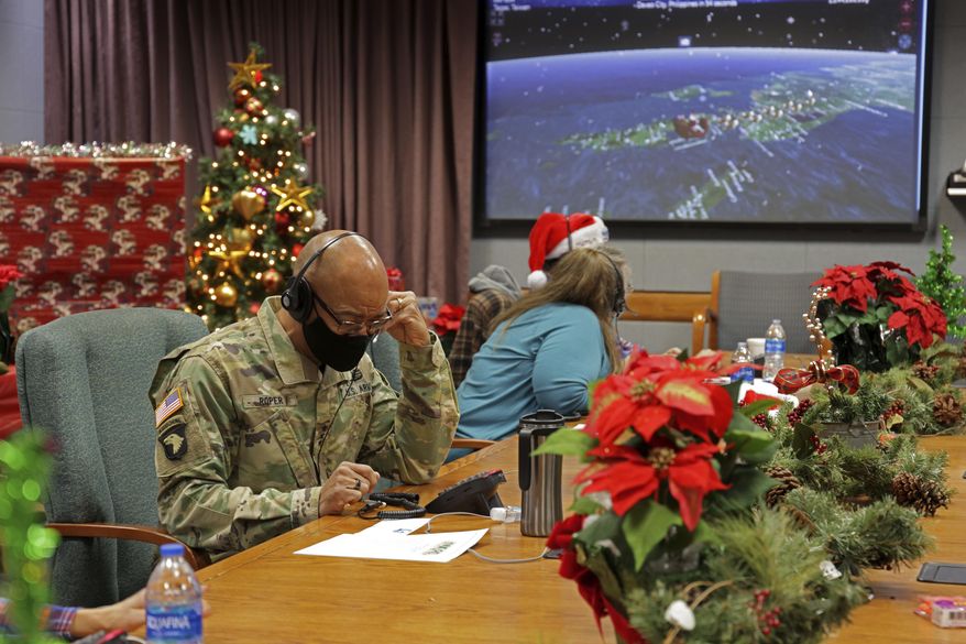 In this photo released by the U.S. Department of Defense, volunteers answer phones and emails from children around the globe during annual NORAD Tracks Santa event at Peterson Air Force Base in Colorado Springs, Colo., on Dec. 24, 2021. The U.S. military agency known for tracking Santa Claus as he delivers presents on Christmas Eve doesn't expect COVID-19 or the "bomb cyclone" hitting North America to impact Saint Nick's global travels this year. NORAD, the North American Aerospace Defense Command, is responsible for monitoring and defending the skies above North America. (Jhomil Bansil/U.S. Department of Defense via AP)