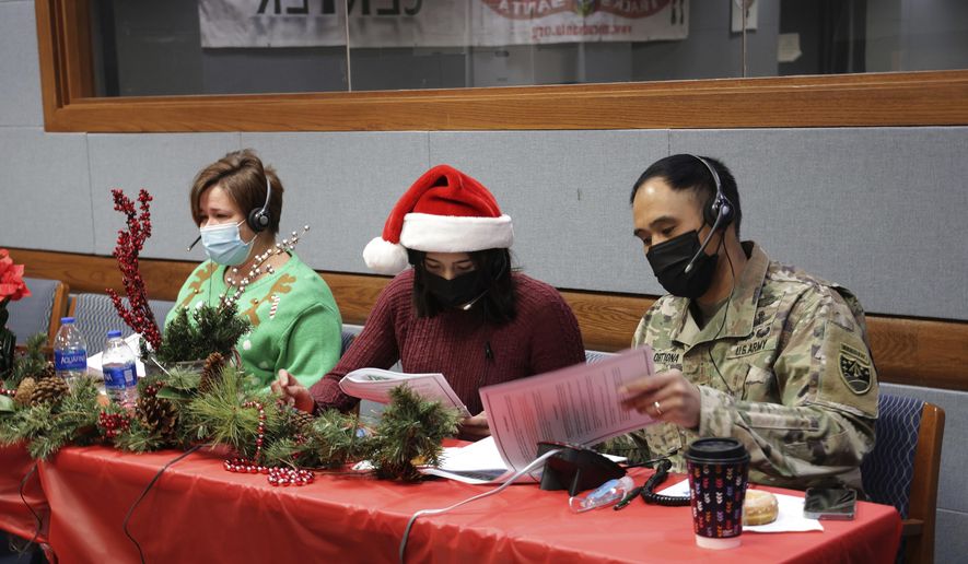 In this photo released by the U.S. Department of Defense, volunteers answer phones and emails from children around the globe during annual NORAD Tracks Santa event at Peterson Air Force Base in Colorado Springs, Colo., on Dec. 24, 2021. The U.S. military agency known for tracking Santa Claus as he delivers presents on Christmas Eve doesn't expect COVID-19 or the "bomb cyclone" hitting North America to impact Saint Nick's global travels this year. NORAD, the North American Aerospace Defense Command, is responsible for monitoring and defending the skies above North America. (Jhomil Bansil/U.S. Department of Defense via AP)