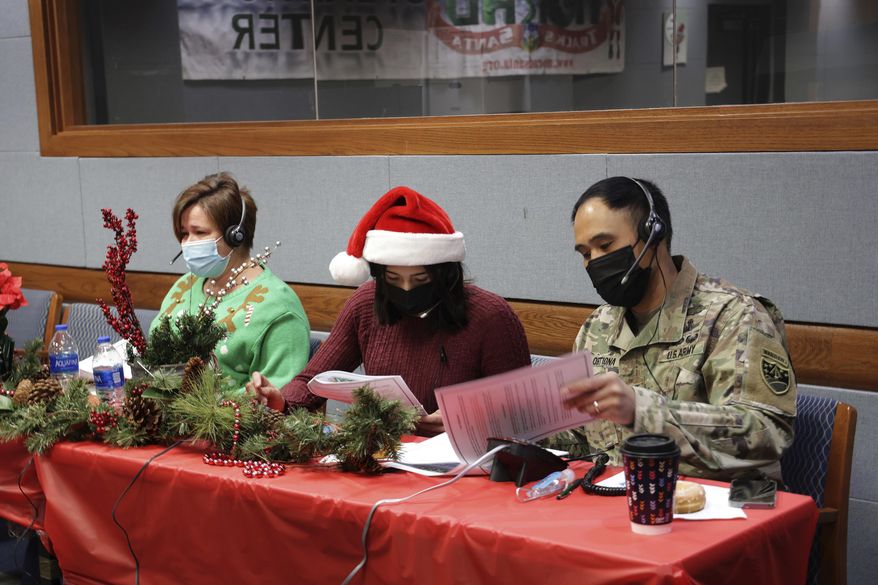 In this photo released by the U.S. Department of Defense, volunteers answer phones and emails from children around the globe during annual NORAD Tracks Santa event at Peterson Air Force Base in Colorado Springs, Colo., on Dec. 24, 2021. The U.S. military agency known for tracking Santa Claus as he delivers presents on Christmas Eve doesn't expect COVID-19 or the "bomb cyclone" hitting North America to impact Saint Nick's global travels this year. NORAD, the North American Aerospace Defense Command, is responsible for monitoring and defending the skies above North America. (Jhomil Bansil/U.S. Department of Defense via AP)