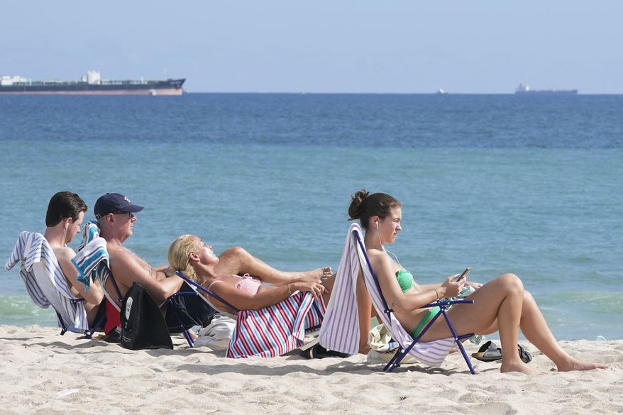 Beachgoers face the sun on Fort Lauderdale beach, Thursday, Dec. 22, 2022, in Fort Lauderdale, Fla. While most of the country is under severe cold weather warning, South Florida's high temperature peaked in the mid 80's. (AP Photo/Marta Lavandier)