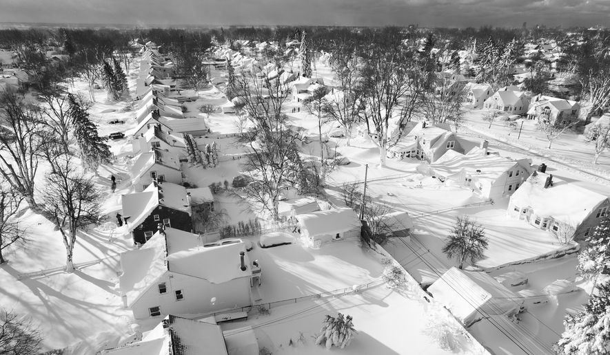 In this drone image, snow blankets a neighborhood, Sunday, Dec. 25, 2022, in Cheektowaga, N.Y. Millions of people hunkered down against a deep freeze Sunday morning to ride out the frigid storm that has killed at least 24 people across the United States and is expected to claim more lives after trapping some residents inside houses with heaping snow drifts and knocking out power to several hundred thousand homes and businesses.(John Waller via AP)