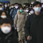 Masked commuters walk through a walkway in between two subway stations as they head to work during the morning rush hour in Beijing on Dec. 20, 2022. Japanese Prime Minister Fumio Kishida announced Tuesday, Dec. 27, that Japan will tighten border controls against COVID-19 by requiring tests for all visitors from China starting Friday as a temporary emergency measure against the surging infections there. (AP Photo/Andy Wong, File)
