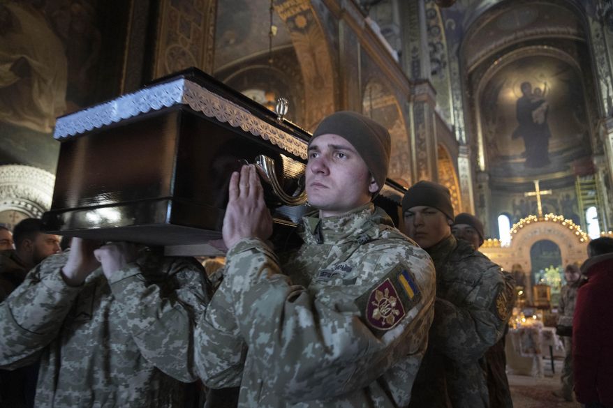 Ukrainian servicemen carry the coffin of their comrade during the funeral ceremony for Volodymyr Yezhov killed in a battlefield with Russian forces, at St. Volodymyr Cathedral in Kyiv, Ukraine, Tuesday, Dec. 27, 2022. Yezhov was a game designer in the development of the game Cossacks 2. He was also one of the authors of the game S.T.A.L.K.E.R.: Clear Sky. Yezhov was also one of the most famous Ukrainian e-sportsmen — played StarCraft under the nickname Fresh. Since the Russian invasion, Volodymyr Yezhov went to the frontline and fought as part of the volunteer squadron. (AP Photo/Efrem Lukatsky)