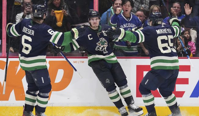 Vancouver Canucks&#x27; Brock Boeser, Bo Horvat and Ilya Mikheyev, from left, celebrate Horvat&#x27;s second goal against the San Jose Sharks, during the third period of an NHL hockey game Tuesday, Dec. 27, 2022, in Vancouver, British Columbia. (Darryl Dyck/The Canadian Press via AP)