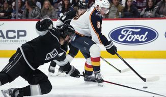 Colorado Avalanche defenseman Cale Makar, center, drives between Los Angeles Kings defenseman Drew Doughty, front, and right wing Adrian Kempe during the first period of an NHL hockey game Thursday, Dec. 29, 2022, in Denver. (AP Photo/David Zalubowski)