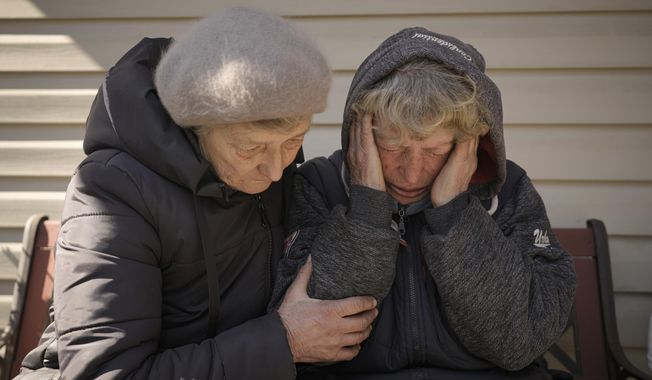 A neighbor comforts Natalia Vlasenko, whose husband, Pavlo Vlasenko, and grandson, Dmytro Chaplyhin, called Dima, were killed by Russian forces, as she cries in her garden in Bucha, Ukraine, Monday, April 4, 2022. Russian soldiers picked up Dima during a March 4 sweep, accused him of being a spotter helping the Ukrainian military. Asked “What would justice be for you?,” the grandmother of 20-year-old Dima says, “I- I- I can’t even- I don’t know. These scoundrels…” (AP Photo/Vadim Ghirda, File)