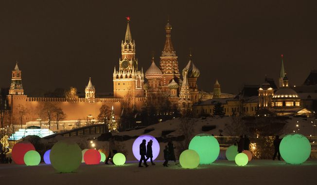 People walk at Zaryadye Park decorated for the New Year and Christmas festivities with the Kremlin Wall, the Spasskaya Tower, and the St. Basil&#x27;s Cathedral in the background in Moscow, Russia, Thursday, Dec. 29, 2022. (AP Photo/Alexander Zemlianichenko)