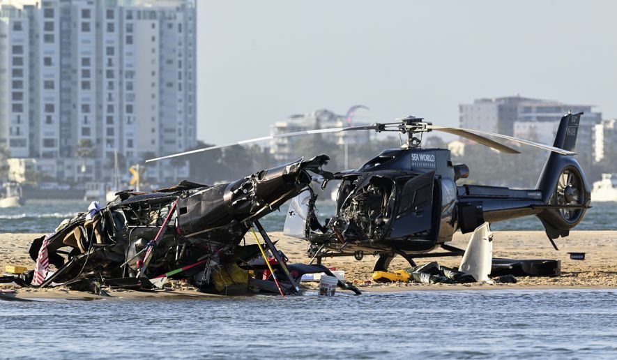 Two crashed helicopters sit on the sand at a collision scene near Sea World, on the Gold Coast, Australia, Monday, Jan. 2, 2023. The two helicopters collided killing several passengers and critically injuring a few others in a crash that drew emergency aid from beachgoers enjoying the water during the southern summer. (Dave Hunt/AAP Image via AP)