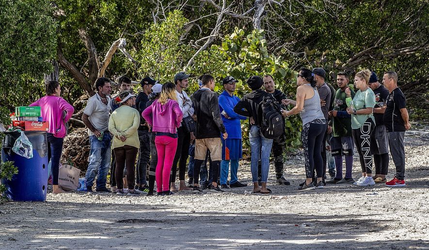 A group of Cuban migrants stand in the sun on the side of U.S. 1 in the Middle Keys island of Duck Key, Fla., Monday Jan. 2, 2023. (Pedro Portal/Miami Herald via AP)