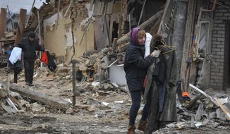 Local residents carry their belongings as they leave their home ruined in the Saturday Russian rocket attack in Zaporizhzhya, Ukraine, Sunday, Jan. 1, 2023. (AP Photo/Andriy Andriyenko)