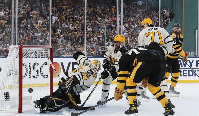 Pittsburgh Penguins goalie Tristan Jarry (35) deflects a shot in front of Boston Bruins&#x27; Jake DeBrusk (74) during the first period of the NHL Winter Classic hockey game, Monday, Jan. 2, 2023, at Fenway Park in Boston. (AP Photo/Michael Dwyer)