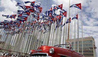 A classic American convertible car passes beside the United States embassy as Cuban flags fly at the Anti-Imperialist Tribune, a massive stage on the Malecon seaside promenade in Havana, Cuba, July 26, 2015. The United States Embassy in Cuba is opening visa and consular services on Wednesday, Jan 4, 2023. It was the first time since a spate of unexplained health incidents among diplomatic staff in 2017 slashed American presence in Havana(AP Photo/Desmond Boylan, File)