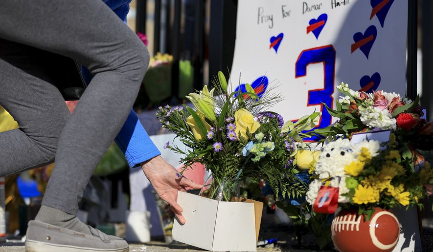 A person leaves flowers for the display set-up for Buffalo Bills&#x27; Damar Hamlin outside of University of Cincinnati Medical Center, Wednesday, Jan. 4, 2023, in Cincinnati. Hamlin was taken to the hospital after collapsing on the field during the Bill&#x27;s NFL football game against the Cincinnati Bengals on Monday night. (AP Photo/Aaron Doster)