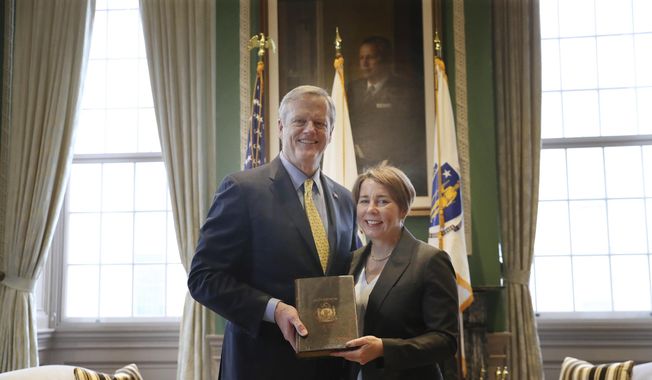Massachusetts Gov. Charlie Baker presents traditional symbols to Gov-elect Maura Healey during a ritual exchange, Wednesday, Jan. 4, 2023, at the State House in Boston. (Nancy Lane/The Boston Herald via AP, Pool)