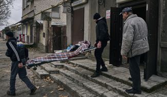 Local residents carry the body of a 20-year-old man killed in Russian shelling in Kherson, Ukraine, Thursday, Jan. 5, 2023. (AP Photo/LIBKOS)