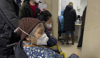 An elderly patient wearing a face mask looks as patients wait to see a doctor at the emergency ward of a hospital in Beijing, Thursday, Jan. 5, 2023. Patients, most of them elderly, are lying on stretchers in hallways and taking oxygen while sitting in wheelchairs as COVID-19 surges in China&#39;s capital Beijing. (AP Photo/Andy Wong)