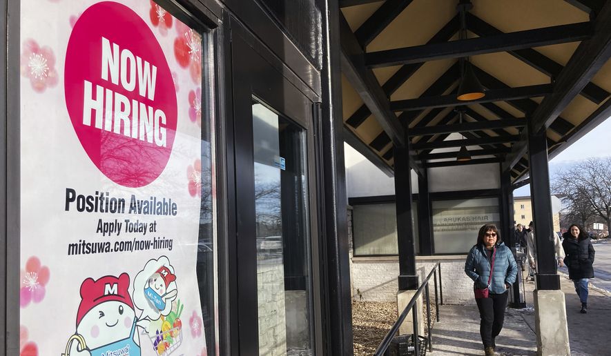 A hiring sign is displayed at a grocery store in Arlington Heights, Ill., Tuesday, Dec. 27, 2022. America’s employers added a solid 223,000 jobs in December, evidence that the economy remains healthy yet also a sign that the Federal Reserve may still have to raise interest rates aggressively to slow growth and cool inflation. (AP Photo/Nam Y. Huh, File)