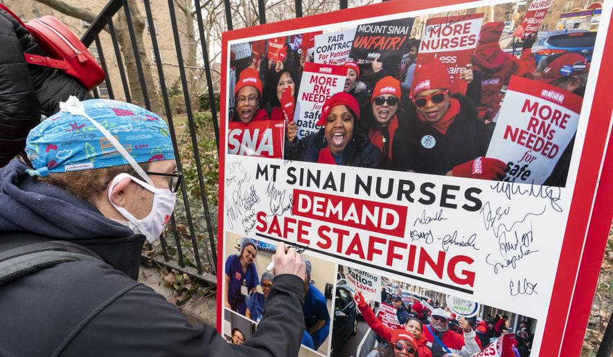 Zach Clapp, a nurse in the Pediatric Cardiac ICU at Mount Sinai Hospital signs a board demanding safe staffing during a rally by NYSNA nurses from NY Presbyterian and Mount Sinai, Tuesday, March 16, 2021, in New York. Negotiations to keep 10,000 New York City nurses from walking off the job headed Friday, Jna. 6, 2023, into a final weekend as some major hospitals braced for a potential strike by sending ambulances elsewhere and transferring such patients as vulnerable newborns. (AP Photo/Mary Altaffer, File)
