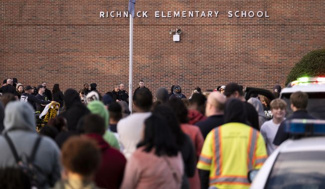 Students and police gather outside of Richneck Elementary School after a shooting, Friday, Jan. 6, 2023 in Newport News, Va. A shooting at a Virginia elementary school sent a teacher to the hospital and ended with “an individual” in custody Friday, police and school officials in the city of Newport News said. (Billy Schuerman/The Virginian-Pilot via AP)