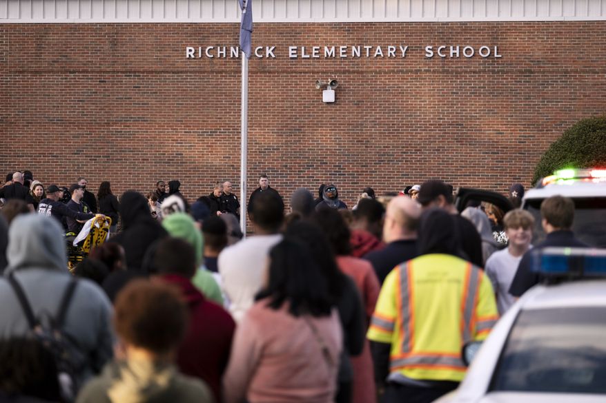 Students and police gather outside of Richneck Elementary School after a shooting, Friday, Jan. 6, 2023 in Newport News, Va. A shooting at a Virginia elementary school sent a teacher to the hospital and ended with “an individual” in custody Friday, police and school officials in the city of Newport News said. (Billy Schuerman/The Virginian-Pilot via AP)