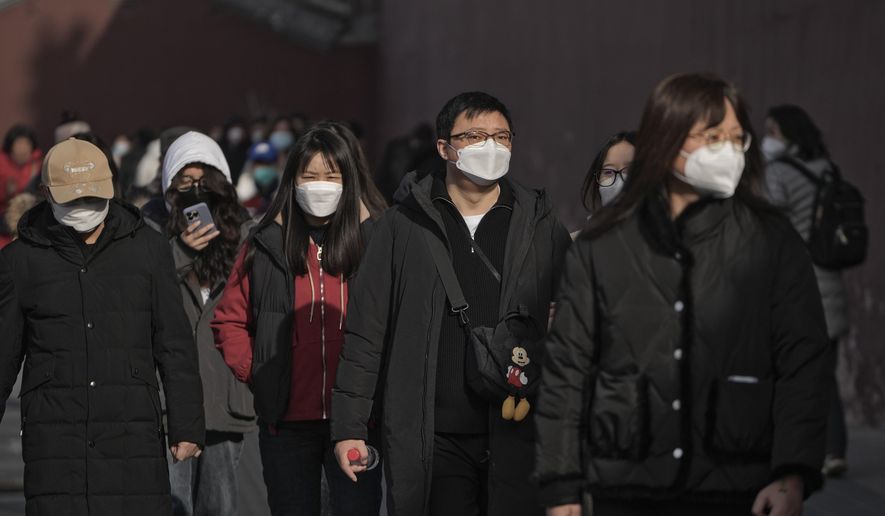 People wearing face masks walk along a street in Beijing, Friday, Jan. 6, 2023. China has suspended or closed the social media accounts of more than 1,000 critics of the government’s policies on the COVID-19 outbreak, as the country moves to further open up. (AP Photo/Andy Wong)