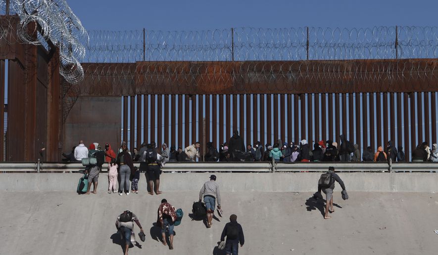Migrants approach the border wall in Ciudad Juarez, Mexico, Dec. 21, 2022, on the other side of the border from El Paso, Texas. President Joe Biden is heading to the U.S.-Mexico border on Sunday, Jan. 8, 2023, for his first visit as president. Biden will stop in El Paso, currently the biggest corridor for illegal crossings. (AP Photo/Christian Chavez, File)