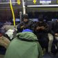 Migrants use their phones inside an idle city bus in their attempt to stay warm while camping outside the Sacred Heart Church in downtown El Paso, Texas, Saturday, Jan. 7, 2023. Around 300 migrants have taken refuge on sidewalks, some of them afraid to seek more formal shelters, amid new restrictions meant to crack down on illegal border crossings. President Joe Biden will visit El Paso on Sunday on his first, politically thorny visit to the southern border. (AP Photo/Andres Leighton)