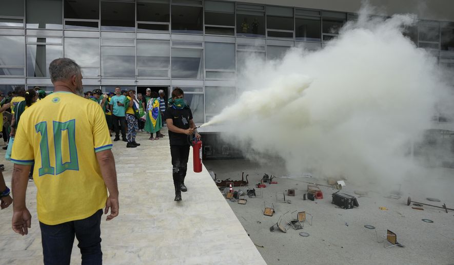 A protester, supporter of Brazil&#x27;s former President Jair Bolsonaro, empties a fire extinguisher after protesters stormed Planalto Palace in Brasilia, Brazil, Sunday, Jan. 8, 2023. Planalto is the official workplace of the president. (AP Photo/Eraldo Peres)