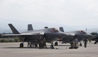 U.S. military personnel work near F-35 fighter jet of the Vermont Air National Guard, parked in the military base at Skopje Airport, North Macedonia, on June 17, 2022. Government officials said Monday, Jan. 9, 2023, that Canada has finalized an agreement with Lockheed Martin Corp and the United States government to purchase 88 F-35 fighter jets. (AP Photo/Boris Grdanoski, File)