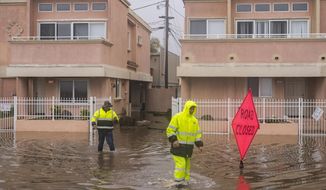 A cleaning crew walks through floodwaters in the Rio Del Mar neighborhood of Aptos, Calif., Monday, Jan. 9, 2023. (AP Photo/Nic Coury)