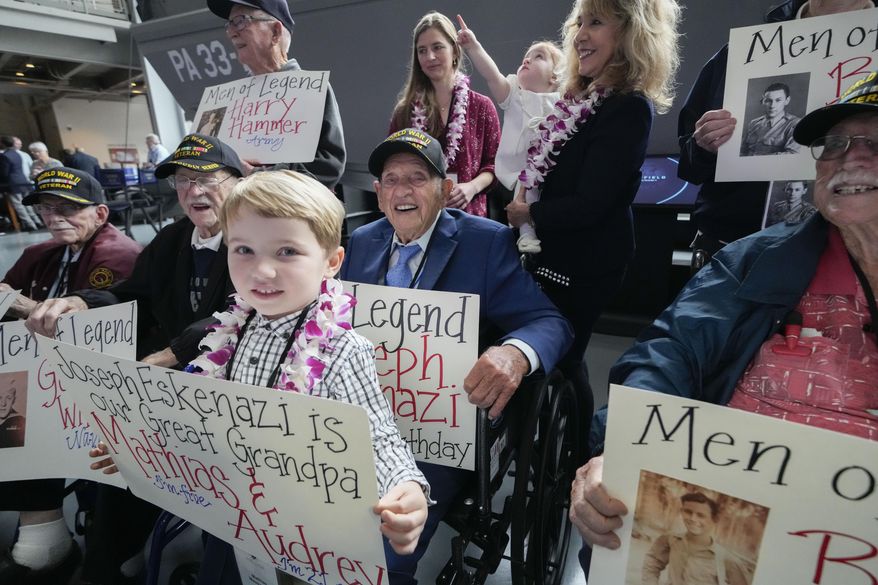 World War II veteran Joseph Eskenazi, who at 104 years and 11 months old is the oldest living veteran to survive the attack on Pearl Harbor, sits with fellow veterans, his great grandchildren Mathias, 4, Audrey, 1, and their grandmother Belinda Mastrangelo, at an event celebrating his upcoming 105th birthday at the National World War II Museum in New Orleans, Wednesday, Jan. 11, 2023. (AP Photo/Gerald Herbert)