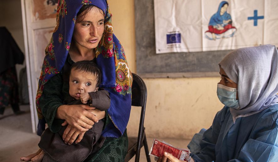 A Save the Children nutrition counselor, right, explains to Nelab, 22, how to feed her 11-month-old daughter, Parsto, with therapeutic food, which is used to treat severe acute malnutrition, in Sar-e-Pul province of Afghanistan, Thursday, Sept. 29, 2022. (Save the Children via AP, File)