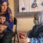 A Save the Children nutrition counselor, right, explains to Nelab, 22, how to feed her 11-month-old daughter, Parsto, with therapeutic food, which is used to treat severe acute malnutrition, in Sar-e-Pul province of Afghanistan, Thursday, Sept. 29, 2022. (Save the Children via AP, File)