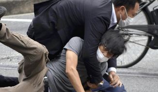 Tetsuya Yamagami, bottom, is detained near the site of gunshots in Nara Prefecture, western Japan, on July 8, 2022. Japanese prosecutors formally charged the suspect in the assassination of former Prime Minister Shinzo Abe with murder, Japan&#39;s NHK public television reported Friday, Jan. 13, 2023. (Katsuhiko Hirano/The Yomiuri Shimbun via AP, File)
